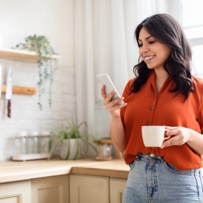 Happy woman with phone and coffee mug