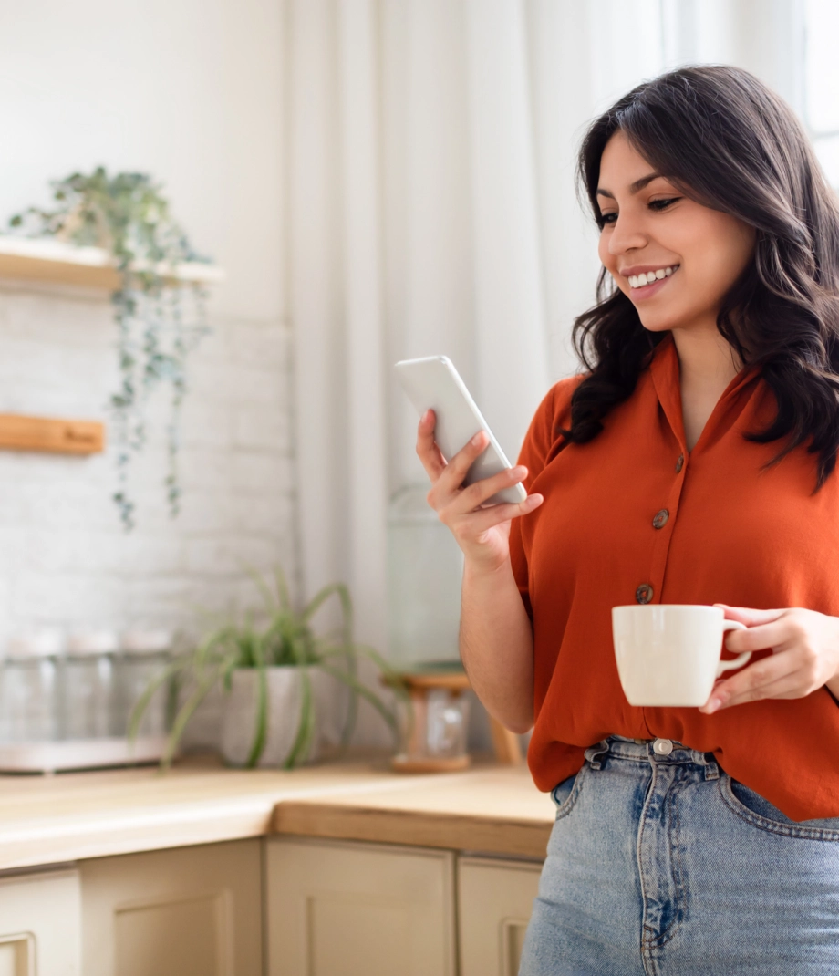Happy woman with phone and coffee mug