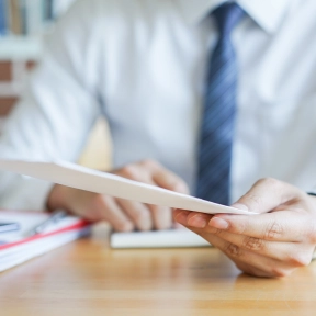 close up manager businessman hand send a white letter of resignation on desk to employee for getting fired concept