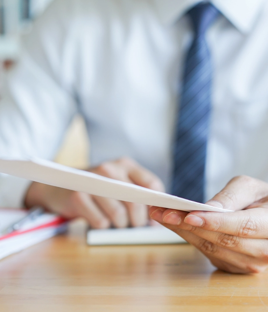 close up manager businessman hand send a white letter of resignation on desk to employee for getting fired concept