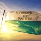 Vaud canton of Switzerland flag textile cloth fabric waving on the top sunrise mist fog