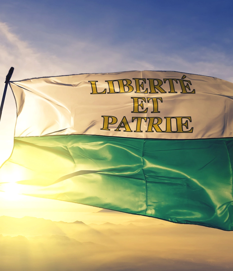 Vaud canton of Switzerland flag textile cloth fabric waving on the top sunrise mist fog